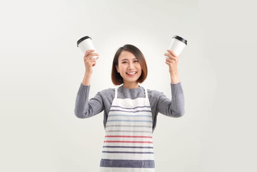 young woman in apron holds two takeaway paper cup isolated over white background