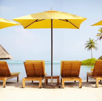 Tropical, deck chairs and umbrella on beach for luxury, travel or summer villa for vacation or holiday. Maldives, leisure and ocean for resort, relax and island with sunshine, outdoor or caribbean.