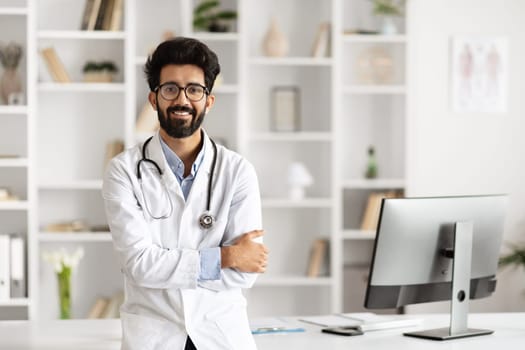 Indian Doctor Poses Beside Computer in Clinic Setting