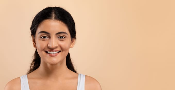 Beauty Concept. Attractive Young Indian Woman With Beautiful Skin Smiling At Camera, Happy Millennial Eastern Female Posing Over Beige Background In Studio, Panorama With Copy Space