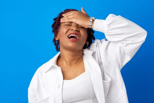 Young afro woman suffering headache against blue background