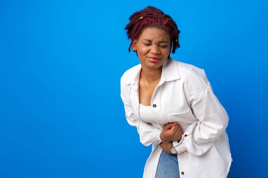Young afro woman suffering stomach ache against blue background