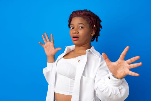 Young african american woman afraid and terrified standing against blue background