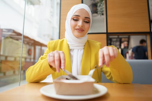 Young muslim woman in hijab having a lunch in cafe