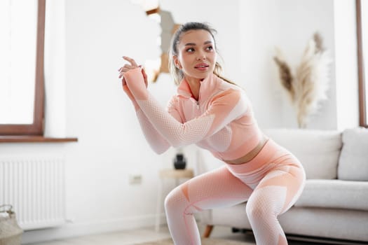 Young fitness girl doing sport exercises at her living room at home