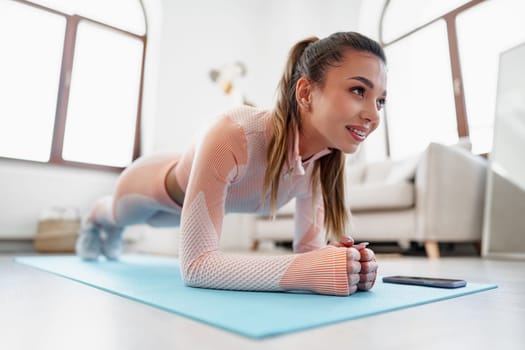Sporty young woman doing plank exercise indoors at home