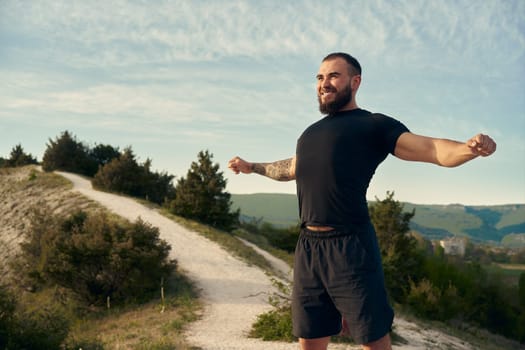 Male athlete warming up before start running in mountains