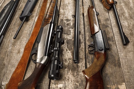 Many hunting rifles on weathered wooden surface
