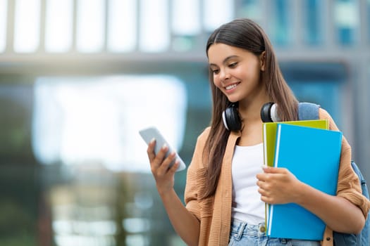 Smiling student using app on smartphone, campus