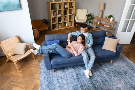 Korean spouses engaging with smartphone fun in living room