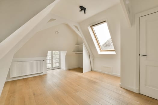 a large attic room with wooden floors and a window