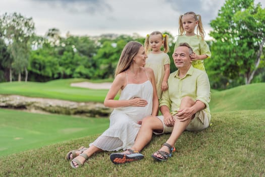 A happy family, two girls, dad, and a pregnant mom, enjoys quality time together on a lush green lawn, creating cherished memories of togetherness