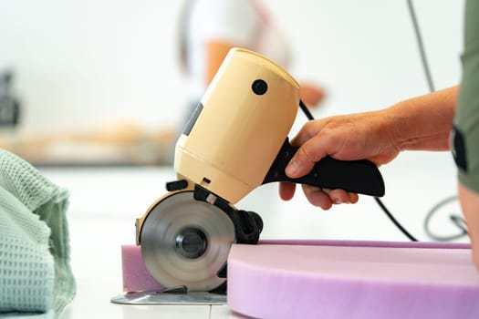 Hands of a furniture master cut a piece of foam with foam cutting machine