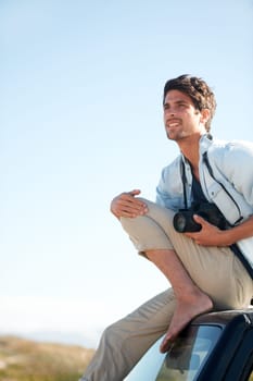 Man, photographer and camera on car or smile for road trip, adventure or journey or thinking with travel. Person, photography or memories for vacation, holiday scenery on drive or blue sky in nature