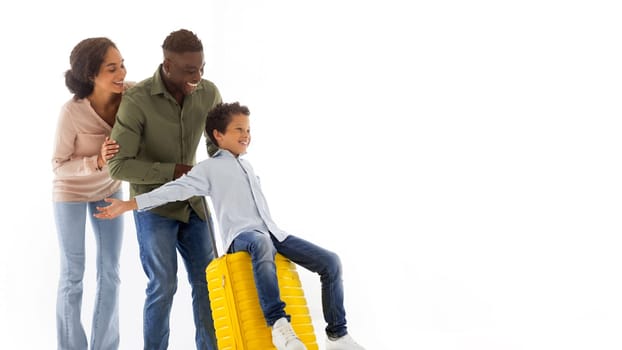Mother and Father Riding Their Happy Kid Son On Yellow Travel Suitcase, Going On Family Vacation Trip, Posing Over White Studio Background, Boy Spreading Arms Like Plane Wings, Panorama, Free Space
