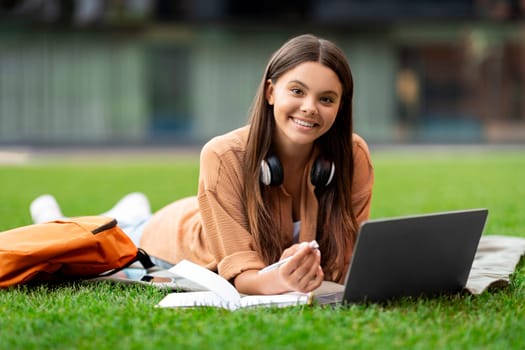Enthusiastic young student engaged with laptop, deserted campus