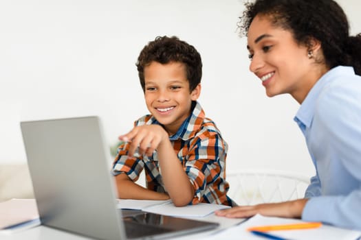 Happy Woman Teaching Little Schoolboy Using Laptop Computer Indoors