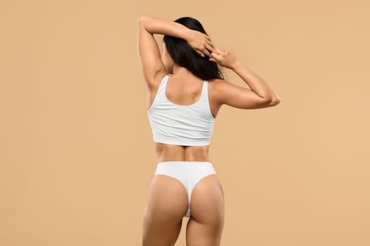 Body Care. Rear View Of Slim Female In Underwear Over Beige Background