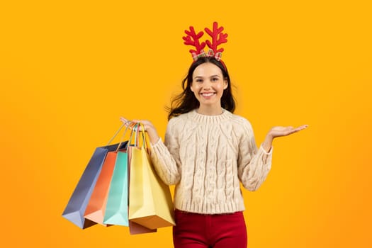Joyful Woman Holding Shopper Bags Buying Xmas Gifts, Yellow Background