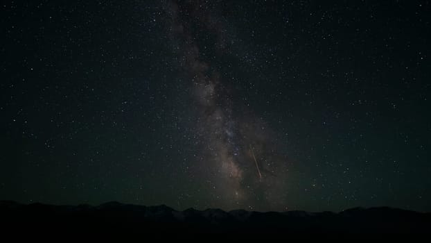 The Milky Way with falling meteorite and mountains