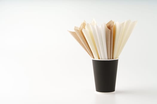 Folded paper napkins in paper cup on white background