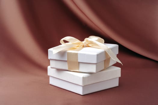 White jewelry boxes on brown silk background