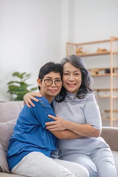 Two retired Asian women hug as they meet and have fun in the living room.