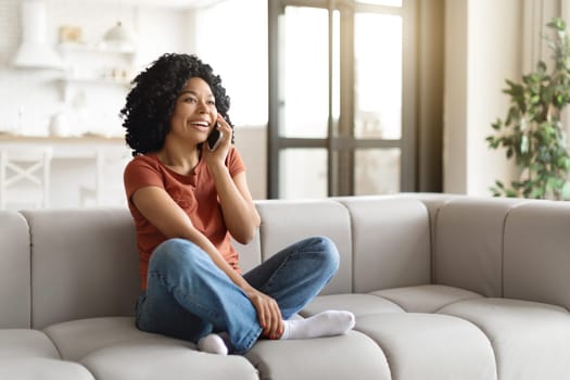 Young Black Woman Having Phone Call While Relaxing On Couch At Home