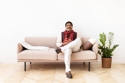 Happy mature hindu man in national costume chilling at home