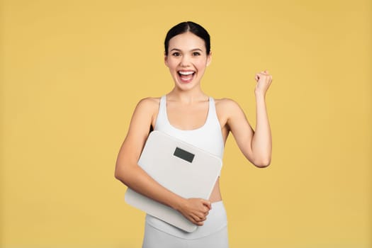 Joyful European woman holding scale, celebrating weight loss