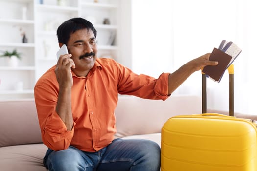 Happy mature indian man preparing for traveling, talking on phone