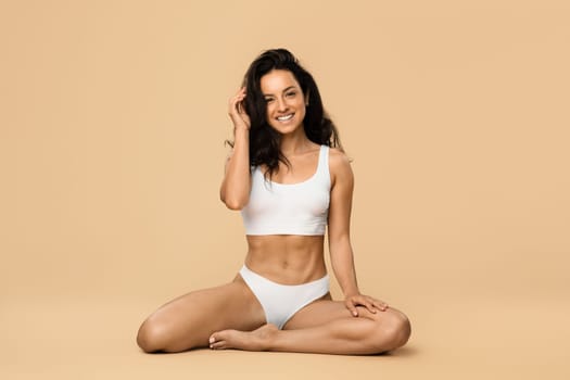 Body Positive. Attractive Female In Underwear Sitting On Floor On Beige Background