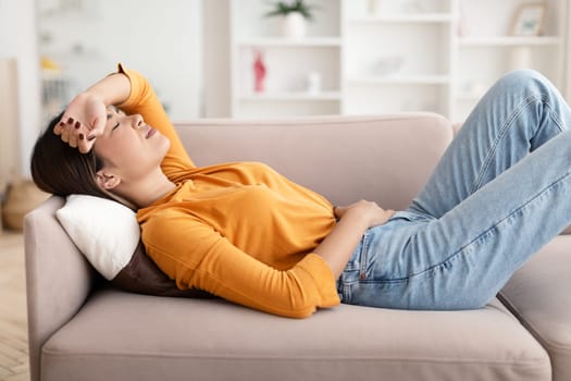Sad despair young asian woman lying on couch