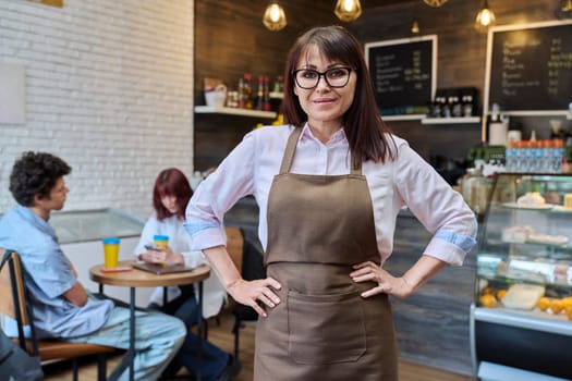 Portrait of confident smiling middle aged woman coffee shop owner, worker