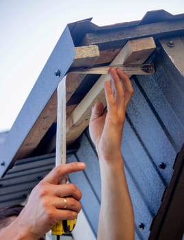 a man repairs the roof, tightens the self-tapping screw with a screwdriver