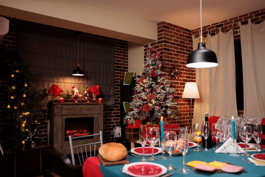 Festive decorated dinning room with christmas feast and beautiful fireplace, seasonal winter celebration with meal and wine. Traditional preparations on holiday for celebrating christmas eve party.