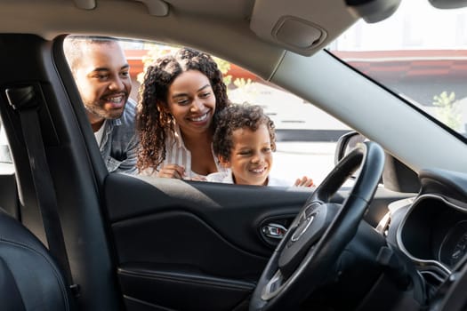 Happy african american family choosing new car at dealership center