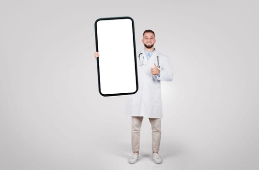 Doctor holding giant smartphone, giving thumbs up