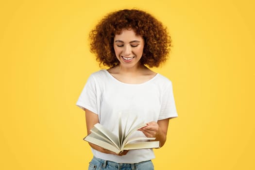 Cheerful smart curly caucasian young lady read book, enjoy spare time
