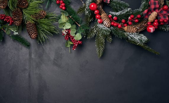Branches and a round Christmas wreath made of fir branches and other decor on a black chalk board