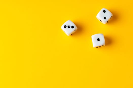 Three dice cubes on yellow background close up