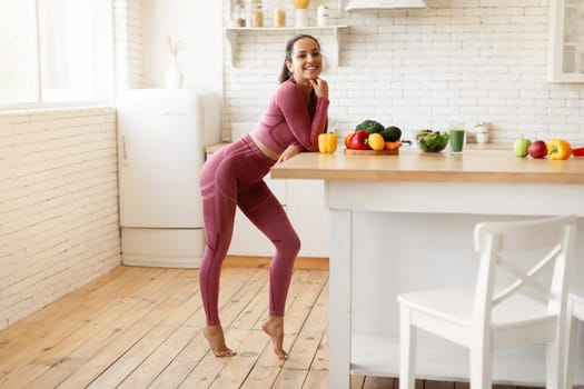Full Length Of Sporty Young Woman In Activewear At Kitchen