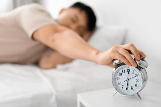 Sleepy Mature Asian Man Turning Off Alarm Clock