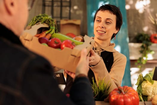 Pleasant female farmer selling fresh organic produce to customer
