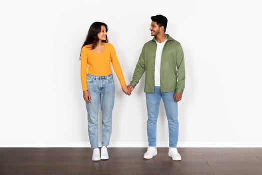 Indian couple holding hands against a white backdrop, full length