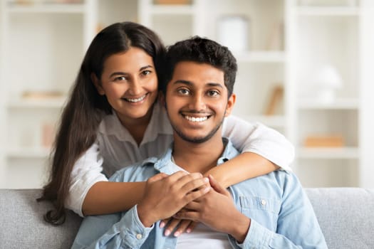 Loving Indian couple embracing on a couch with a joyful smile