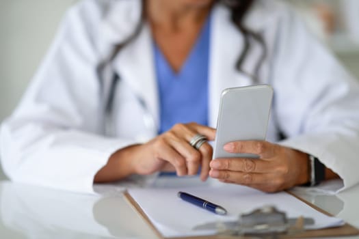 Cropped of woman physician using smartphone with medical app