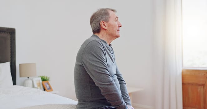 Lonely, senior man and thinking in bedroom with depression, anxiety or mental health in retirement. Tired, elderly person and remember grief or loss in morning, home or sad in the house with a memory