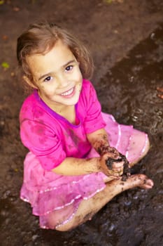 Girl, child and portrait with smile in mud for freedom, playing and muddy fun in sunshine weather or outdoor. Kid, female and face of person with happiness for activity, enjoyment and relax in dirt