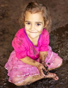 Girl, kid and portrait with smile in mud for freedom, playing and muddy fun in sunshine weather or outdoor. Child, female and face of person with happiness for activity, enjoyment and relax in dirt